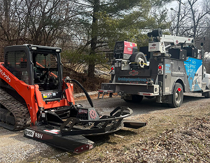 Red skid steer with a rotary cutter.