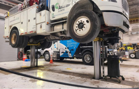 White truck lifted on a hydraulic lift.