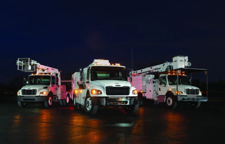 Three utility trucks parked at night.