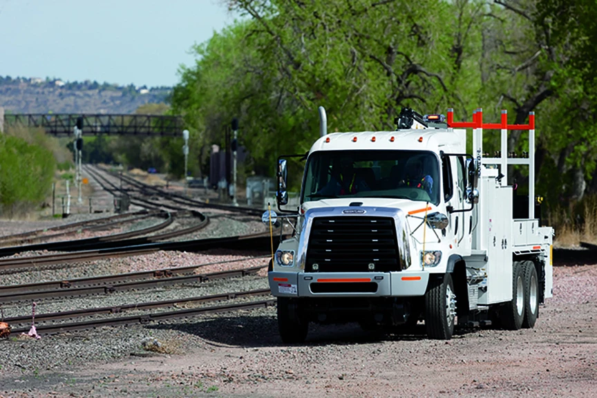 White truck on railroad tracks.