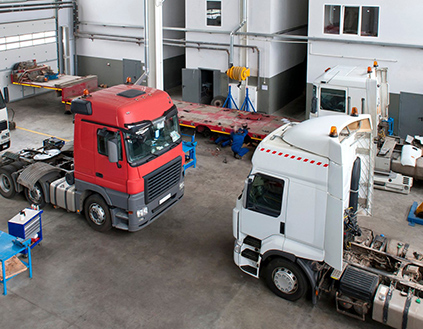 Two semi trucks in a repair shop.